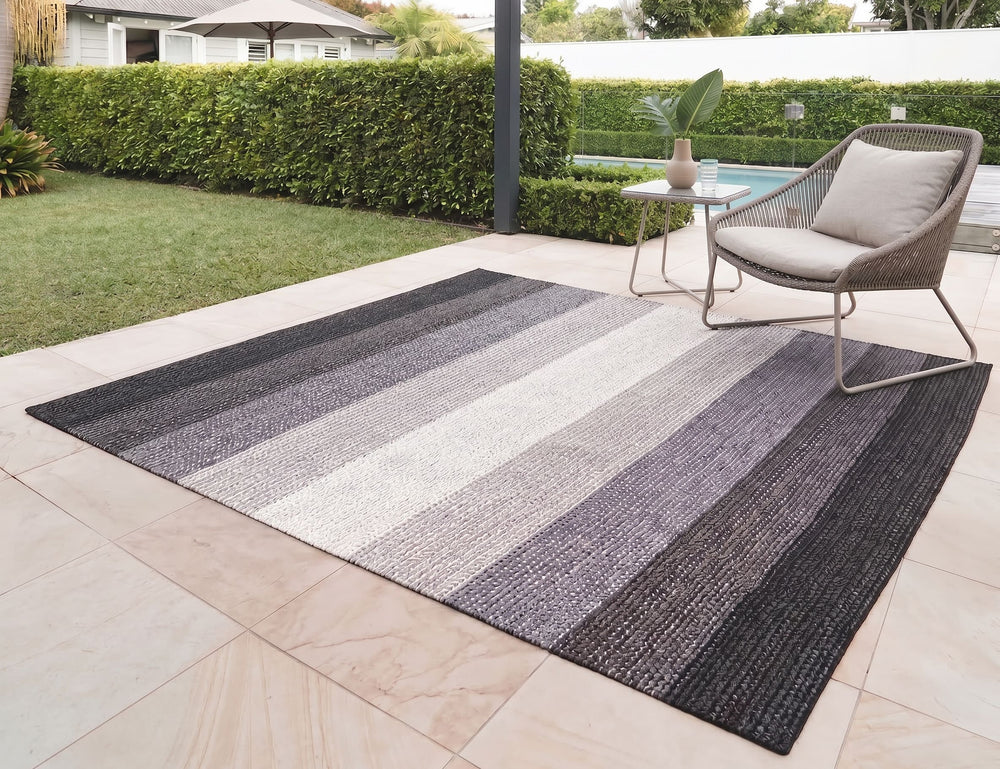 Striped outdoor rug on a patio with a chair and table in the background
