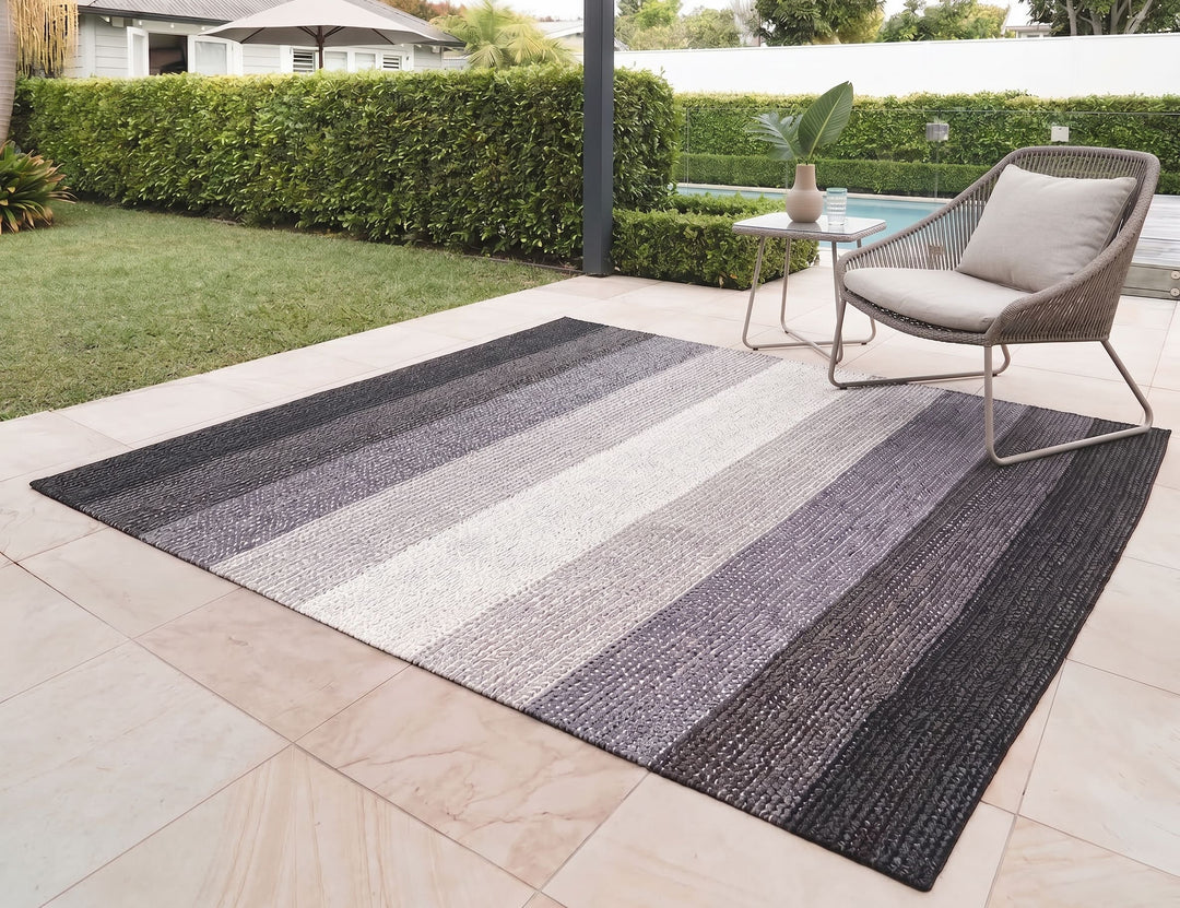 Striped outdoor rug on a patio with a chair and table in the background